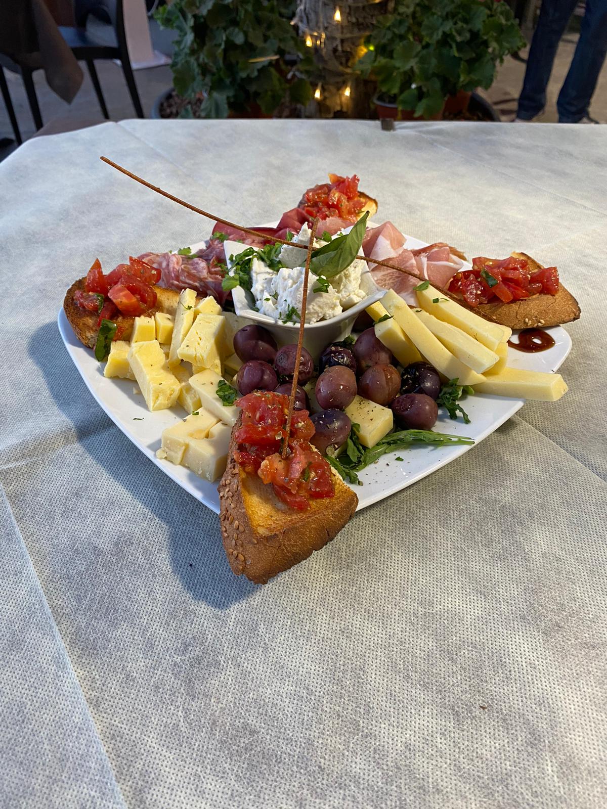 An antipasto platter of cured meats, cheeses, olives and bruschetta on the table