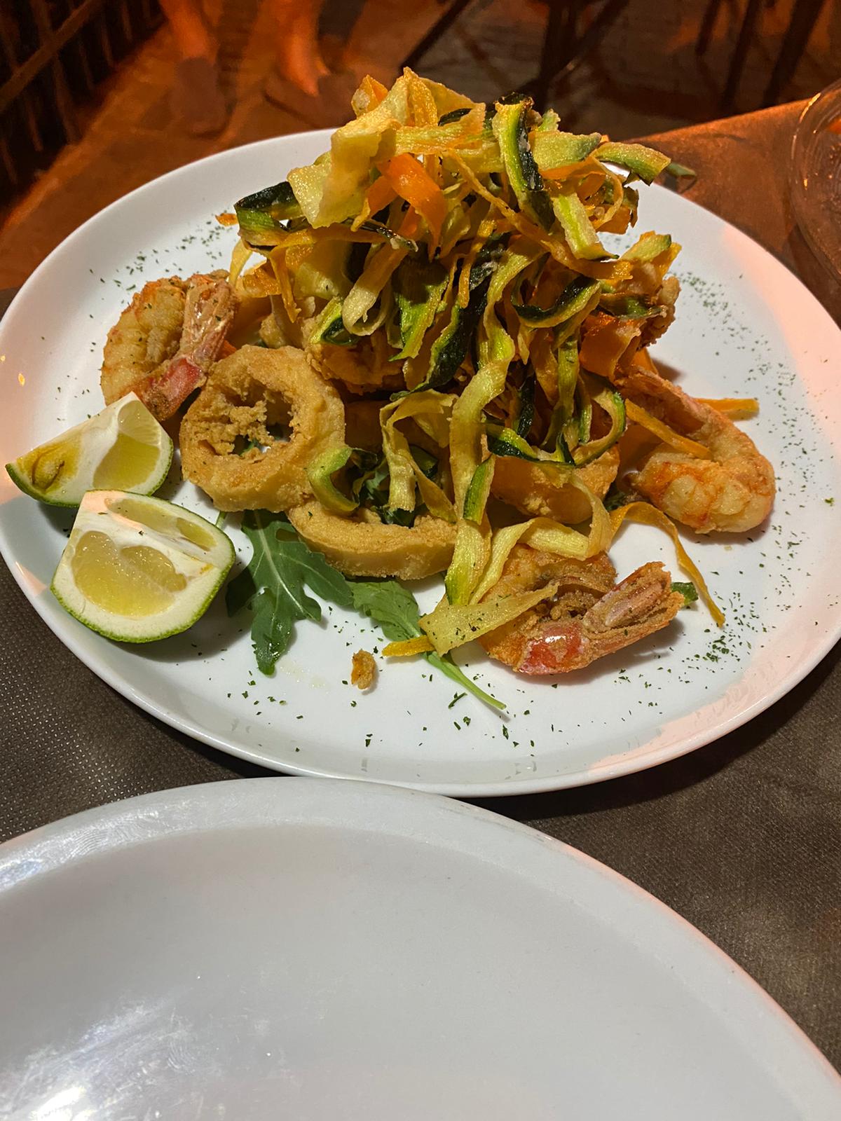 Fried prawns, calamari and courgette with lemon, under the terrace lamps at night
